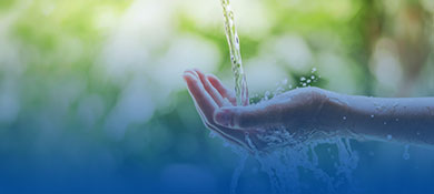 Fließendes Wasser über einer Hand als Darstellung nachhaltiger Komplexbildner für Reinigungsformulierungen